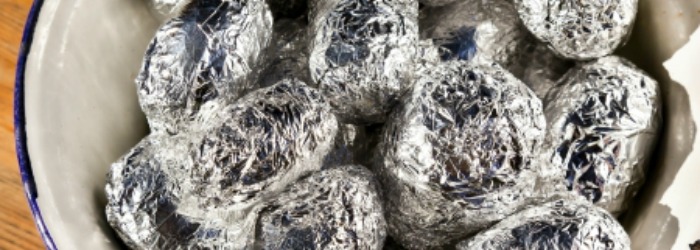 Image of foil wrapped baked potatoes. If you're cooking for a large group such as a women's retreat or group gathering, this recipe for slow cooker baked potatoes is the best!